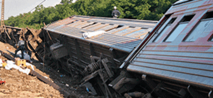 Сбившиеся в кучу вагоны поезда лежат рядом с рельсами, колесами вверх