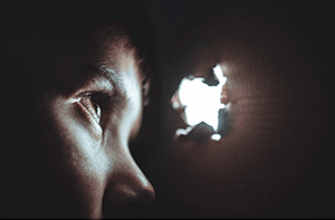 Мальчик спрятался в картонной коробке и со страхом наблюдает через дырочку— в любую секунду может прозвучать звук скримера