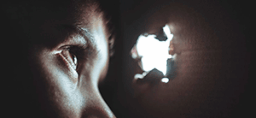 Мальчик спрятался в картонной коробке и со страхом наблюдает через дырочку— в любую секунду может прозвучать звук скримера