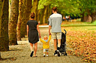 Звук городского парка слушает молодая семья, прогуливающаяся по дорожкам парка