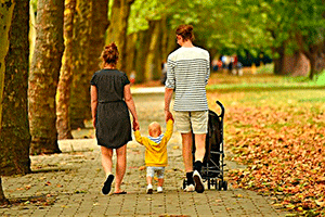  Звук городского парка слушает молодая семья, прогуливающаяся по дорожкам парка
