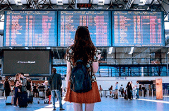 Звуки аэропорта скачать — девушка стоит перед табло с расписанием самолетов