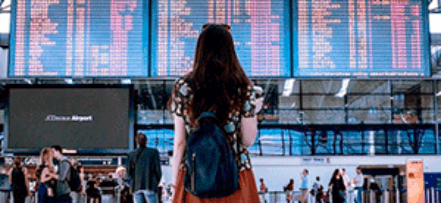 Звуки аэропорта скачать — девушка стоит перед табло с расписанием самолетов