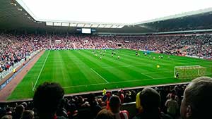 Звуки футбола — на фото футбольное поле с игроками на стадионе с трибунами